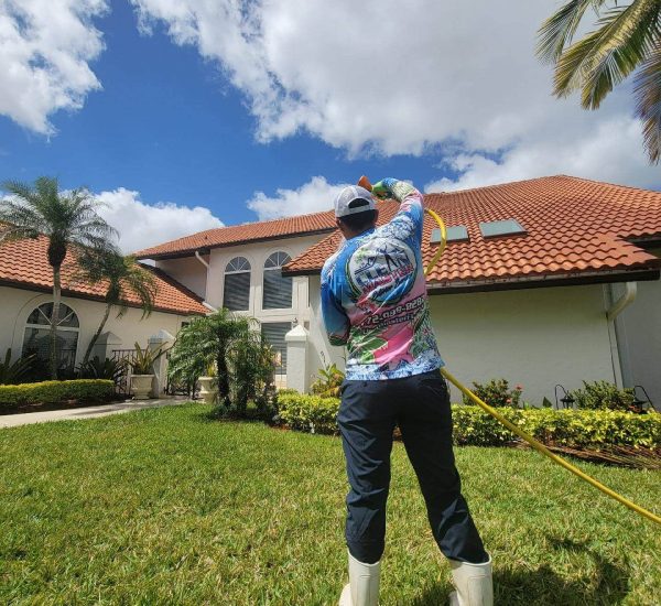 Clean Master technician performing professional house washing in Hobe Sound, Florida using soft wash equipment to clean exterior walls safely and effectively.