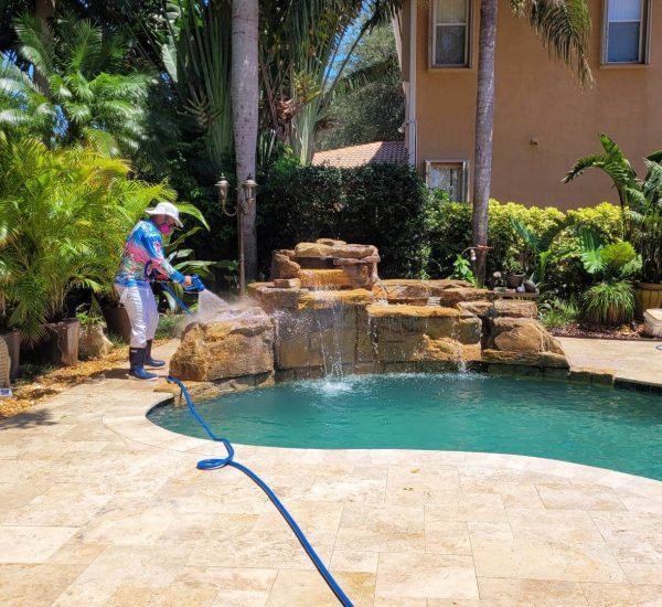 Clean Master technician pressure washing a curb in Hobe Sound, Florida to remove dirt and grime using professional exterior cleaning equipment.